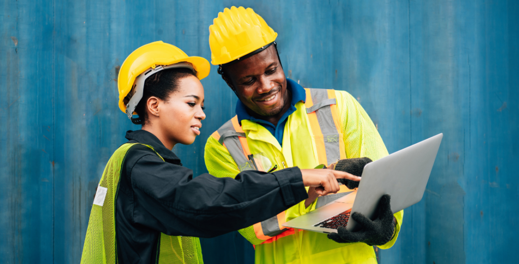 Two construction workers gesturing at a laptop
