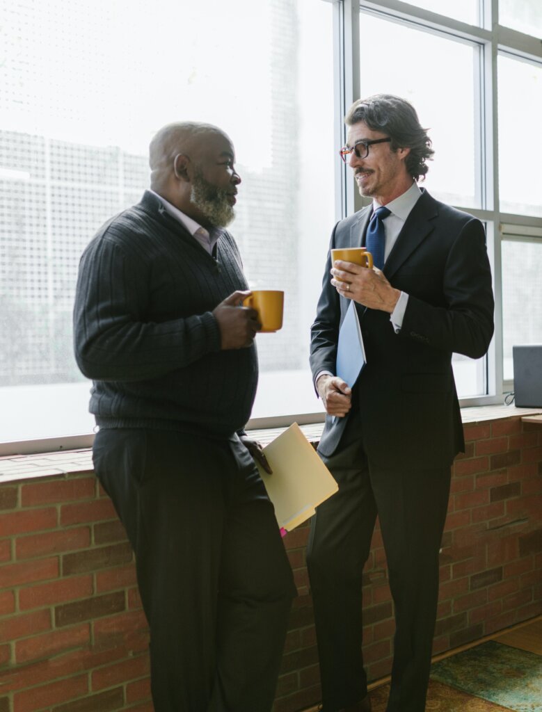 Two businesspeople holding folders chat over coffee